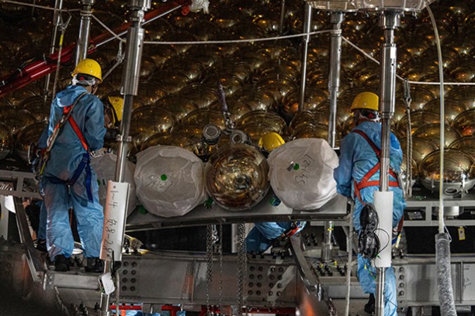 Four workers with hard hats and overalls are surrounded by golden orbs.